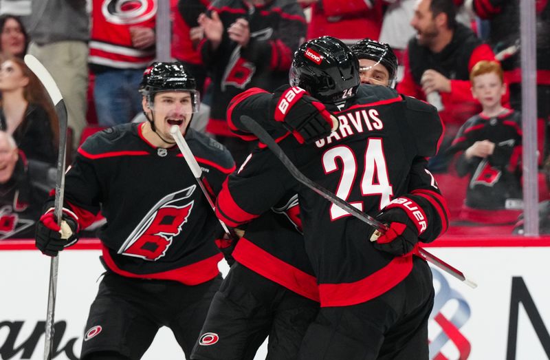 Nov 25, 2024; Raleigh, North Carolina, USA;  Carolina Hurricanes center Sebastian Aho (20) is congratulated by defenseman Dmitry Orlov (7) and center Seth Jarvis (24) after his goal against the Dallas Stars during the third period at Lenovo Center. Mandatory Credit: James Guillory-Imagn Images