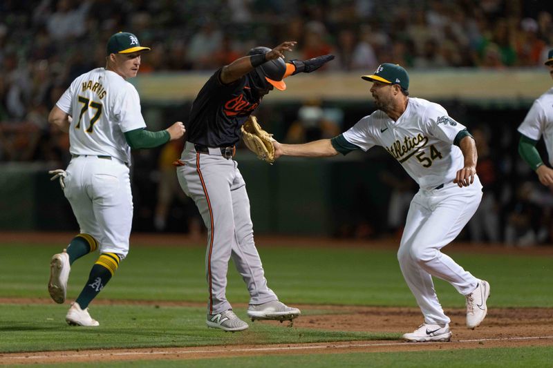 Jul 5, 2024; Oakland, California, USA;  Oakland Athletics pitcher Scott Alexander (54) tags out Baltimore Orioles outfielder Cedric Mullins (31) on a pickle during the ninth inning at Oakland-Alameda County Coliseum. Mandatory Credit: Stan Szeto-USA TODAY Sports