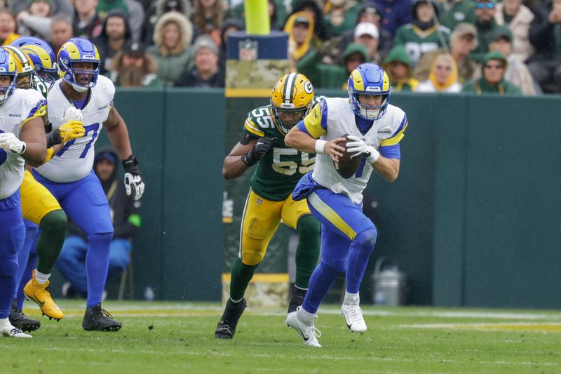 Los Angeles Rams quarterback Brett Rypien (11) is chased out of the pocket by Green Bay Packers linebacker Kingsley Enagbare (55) during an NFL football game between the Green Bay Packers and Los Angeles Rams Sunday, Nov. 5, 2023, in Green Bay, Wis. (AP Photo/Matt Ludtke)