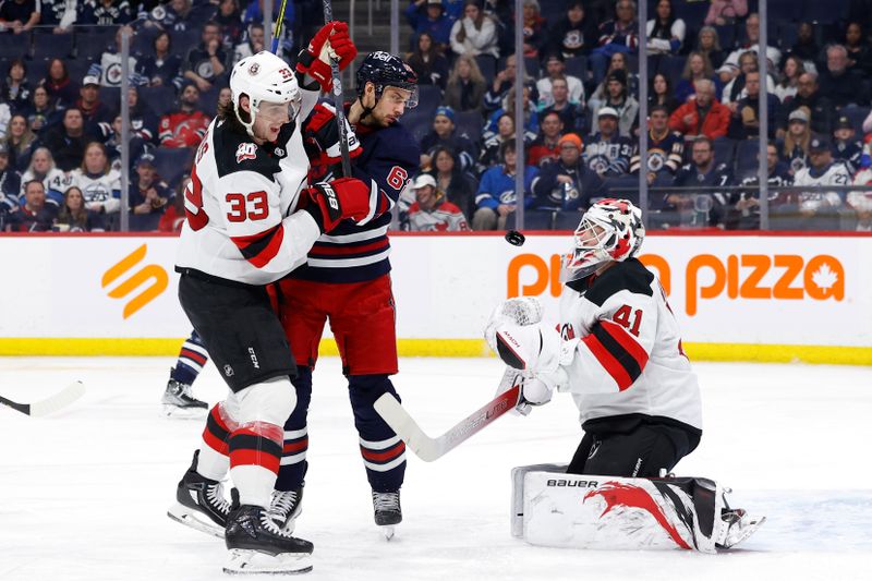 Apr 2, 2023; Winnipeg, Manitoba, CAN; New Jersey Devils defenseman Ryan Graves (33) and Winnipeg Jets right wing Nino Niederreiter (62) watch as New Jersey Devils goaltender Vitek Vanecek (41) stops a shot in the second period at Canada Life Centre. Mandatory Credit: James Carey Lauder-USA TODAY Sports