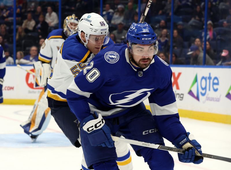 Dec 19, 2023; Tampa, Florida, USA; Tampa Bay Lightning left wing Nicholas Paul (20) and St. Louis Blues defenseman Colton Parayko (55) go after the puck during the third period at Amalie Arena. Mandatory Credit: Kim Klement Neitzel-USA TODAY Sports