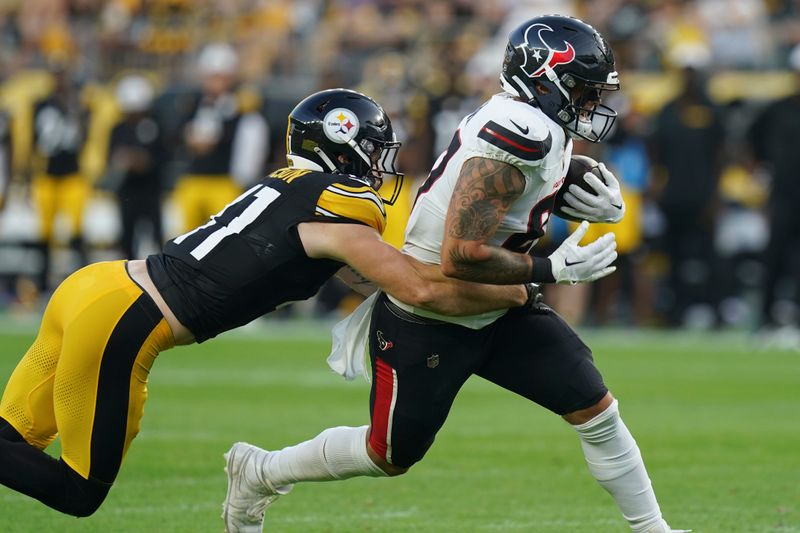 Houston Texans tight end Cade Stover, right, carries defended by Pittsburgh Steelers linebacker Payton Wilson, left, in the first half of a preseason NFL football game, Friday, Aug. 9, 2024, in Pittsburgh. (AP Photo/Matt Freed)