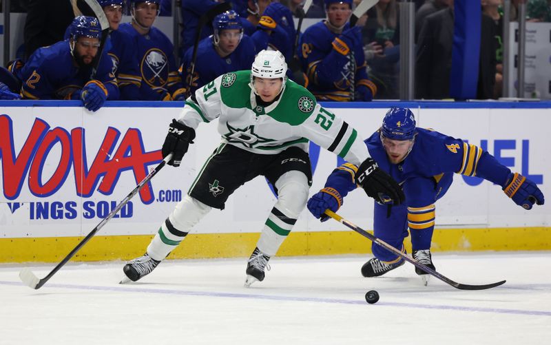 Oct 22, 2024; Buffalo, New York, USA;  Dallas Stars left wing Jason Robertson (21) and Buffalo Sabres defenseman Bowen Byram (4) go after a loose puck during the first period at KeyBank Center. Mandatory Credit: Timothy T. Ludwig-Imagn Images