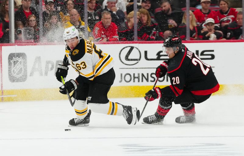 Oct 31, 2024; Raleigh, North Carolina, USA;  Boston Bruins left wing Brad Marchand (63) skates with the puck against Carolina Hurricanes center Sebastian Aho (20) during the second period at Lenovo Center. Mandatory Credit: James Guillory-Imagn Images