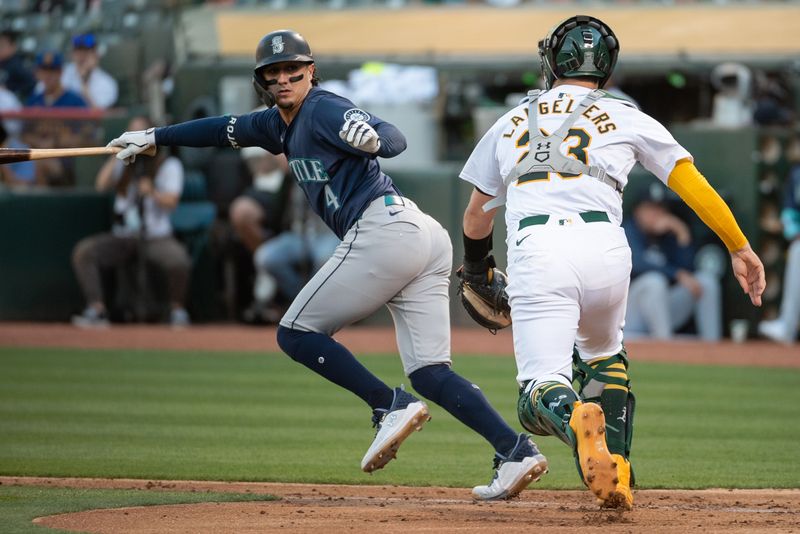 Jun 4, 2024; Oakland, California, USA; Seattle Mariners third base Josh Rojas (4) attempts to avoid a tag from Oakland Athletics catcher Shea Langeliers (23) during the third inning at Oakland-Alameda County Coliseum. Mandatory Credit: Ed Szczepanski-USA TODAY Sports