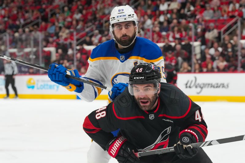 Jan 19, 2026; Raleigh, North Carolina, USA;  Buffalo Sabres right wing Alex Tuch (89) and Carolina Hurricanes left wing Jordan Martinook (48) chase after the puck during the first period at Lenovo Center. Mandatory Credit: James Guillory-Imagn Images