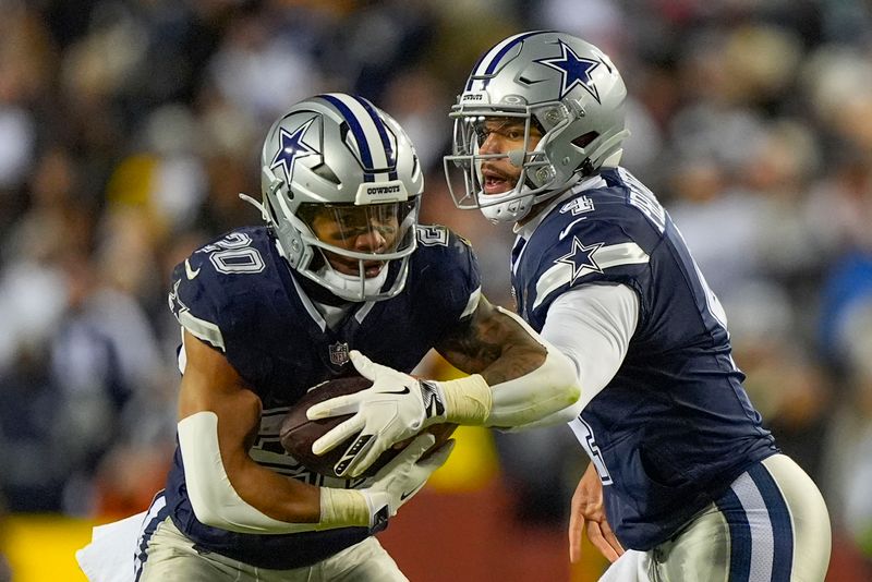 Dallas Cowboys quarterback Dak Prescott (4) handing off the ball to running back Tony Pollard (20) during the first half of an NFL football game against the Washington Commanders, Sunday, Jan. 7, 2024, in Landover, Md. (AP Photo/Mark Schiefelbein)