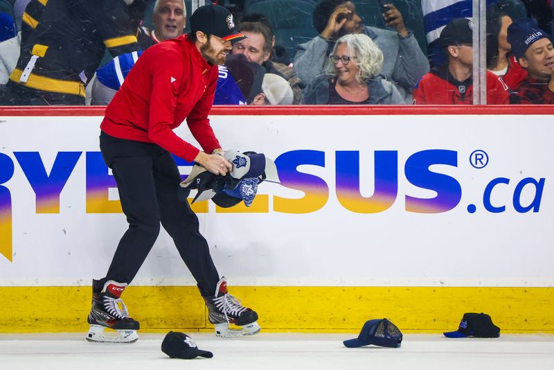 Jan 18, 2024; Calgary, Alberta, CAN; Calgary Flames ice crew members collect hats thrown on the ice for Toronto Maple Leafs center Auston Matthews (34) goal during the second period against the Calgary Flames at Scotiabank Saddledome. Mandatory Credit: Sergei Belski-USA TODAY Sports