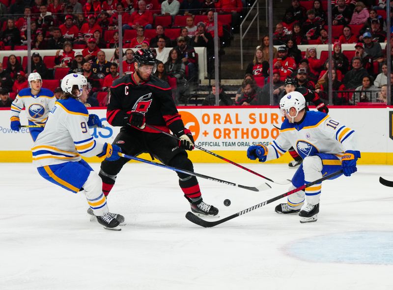 Dec 2, 2023; Raleigh, North Carolina, USA; Buffalo Sabres defenseman Henri Jokiharju (10) and left wing Zach Benson (9) stops the shot attempt  by Carolina Hurricanes center Jordan Staal (11) during the first period at PNC Arena. Mandatory Credit: James Guillory-USA TODAY Sports