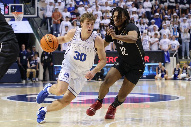 Feb 13, 2024; Provo, Utah, USA; Brigham Young Cougars guard Dallin Hall (30) dribbles past Central Florida Knights guard DeMarr Langford Jr. (12) during the second half at Marriott Center. Mandatory Credit: Rob Gray-USA TODAY Sports