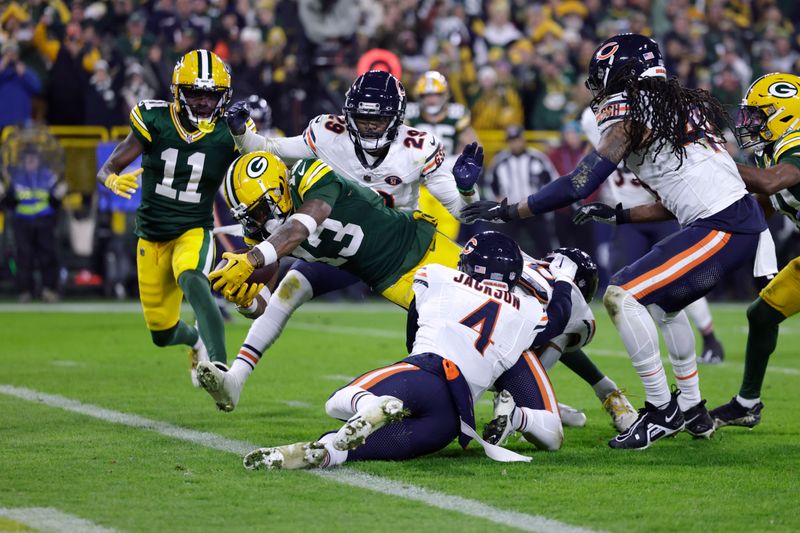 Green Bay Packers wide receiver Dontayvion Wicks (13) dives into the end zone past Chicago Bears cornerback Tyrique Stevenson (29) and safety Eddie Jackson (4) for a touchdown during the second half of an NFL football game Sunday, Jan. 7, 2024, in Green Bay, Wis. (AP Photo/Matt Ludtke)