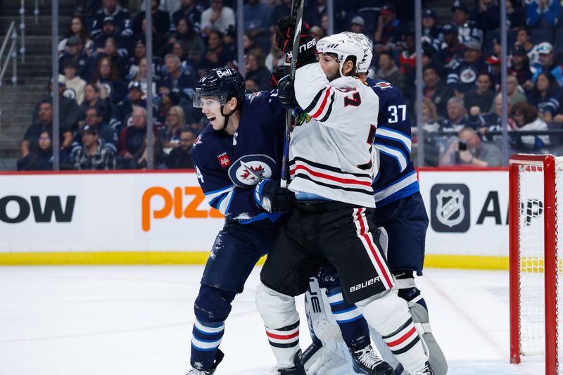 Oct 11, 2024; Winnipeg, Manitoba, CAN;  Winnipeg Jets defenseman Hayden Fleury (24) jostles for position with Chicago Blackhawks forward Patrick Maroon (77) during the first period at Canada Life Centre. Mandatory Credit: Terrence Lee-Imagn Images