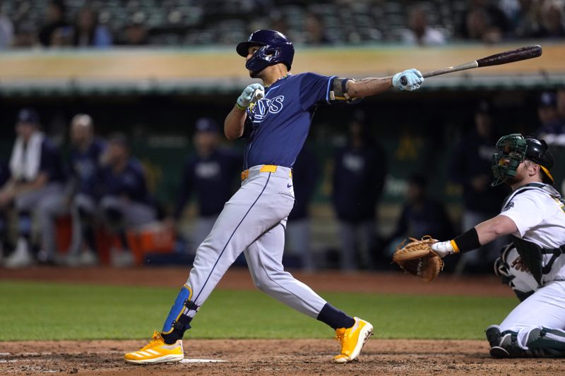 Aug 21, 2024; Oakland, California, USA; Tampa Bay Rays center fielder Jose Siri (22) hits a home run against the Oakland Athletics during the seventh inning at Oakland-Alameda County Coliseum. Mandatory Credit: Darren Yamashita-USA TODAY Sports