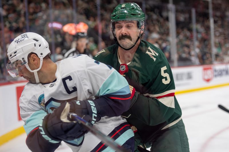 Oct 12, 2024; Saint Paul, Minnesota, USA; Minnesota Wild defenseman Jake Middleton (5) checks Seattle Kraken right wing Jordan Eberle (7) in the third period at Xcel Energy Center. Mandatory Credit: Matt Blewett-Imagn Images