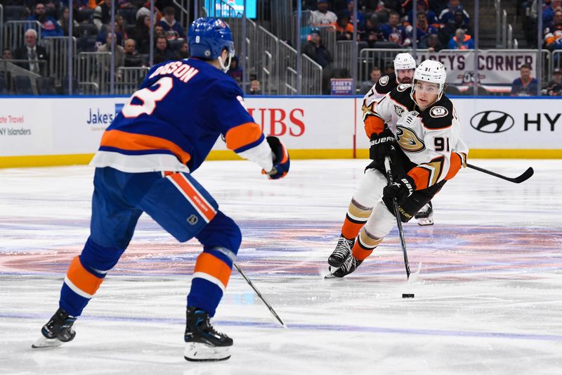 Dec 13, 2023; Elmont, New York, USA; Anaheim Ducks center Leo Carlsson (91) skates the puck across the blue line defended by New York Islanders defenseman Noah Dobson (8) during the third period at UBS Arena. Mandatory Credit: Dennis Schneidler-USA TODAY Sports