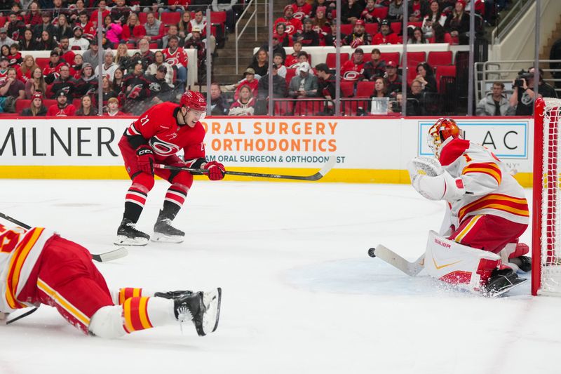Nov 30, 2025; Raleigh, North Carolina, USA;  Carolina Hurricanes defenseman Alexander Nikishin (21) shot attempt is stopped by Calgary Flames goaltender Devin Cooley (1) during the first period at Lenovo Center. Mandatory Credit: James Guillory-Imagn Images