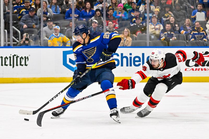 Nov 3, 2023; St. Louis, Missouri, USA;  St. Louis Blues center Jordan Kyrou (25) controls the puck as New Jersey Devils defenseman Kevin Bahl (88) defends during the second period at Enterprise Center. Mandatory Credit: Jeff Curry-USA TODAY Sports