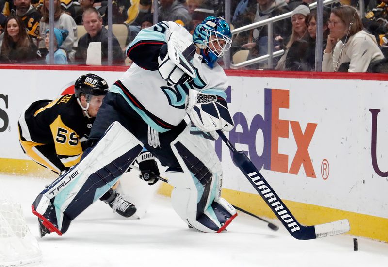 Jan 15, 2024; Pittsburgh, Pennsylvania, USA; Seattle Kraken goaltender Joey Daccord (35) clears the puck from behind the net as Pittsburgh Penguins left wing Jake Guentzel (59) pressures during the first period at PPG Paints Arena. Mandatory Credit: Charles LeClaire-USA TODAY Sports