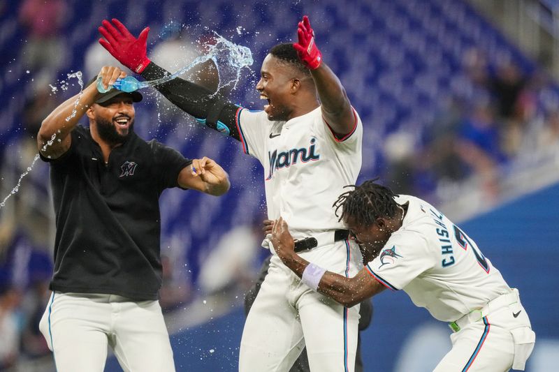 May 2, 2024; Miami, Florida, USA;  Miami Marlins right fielder Jesús Sánchez, center, celebrates the game winning hit in the tenth inning against the Colorado Rockies at loanDepot Park with Sandy Alcantara, left, and Miami Marlins center fielder Jazz Chisholm Jr. (2). Mandatory Credit: Jim Rassol-USA TODAY Sports