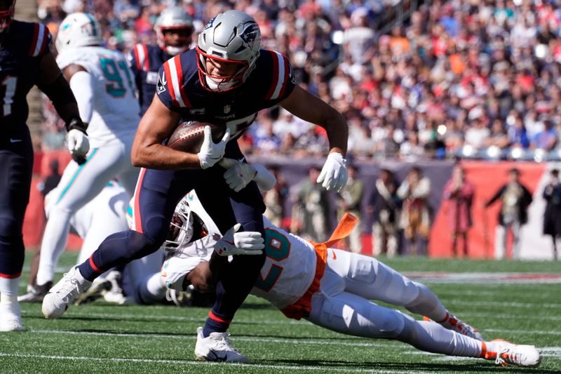 New England Patriots tight end Hunter Henry, left, tries to break free from a tackle during the first half of an NFL football game against the Miami Dolphins, Sunday, Oct. 6, 2024, in Foxborough, Mass. (AP Photo/Michael Dwyer)