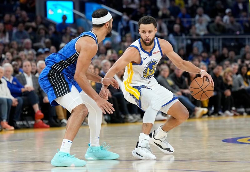 SAN FRANCISCO, CALIFORNIA - JANUARY 02: Stephen Curry #30 of the Golden State Warriors dribbles the ball while being guarded by Jalen Suggs #4 of the Orlando Magic during the fourth quarter of an NBA basketball game at Chase Center on January 02, 2024 in San Francisco, California. NOTE TO USER: User expressly acknowledges and agrees that, by downloading and or using this photograph, User is consenting to the terms and conditions of the Getty Images License Agreement. (Photo by Thearon W. Henderson/Getty Images)