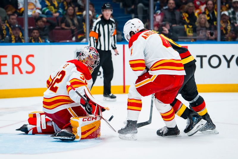 Oct 9, 2025; Vancouver, British Columbia, CAN; Calgary Flames goalie Dustin Wolf (32) makes a save as defenseman Rasmus Andersson (4) battles with Vancouver Canucks forward Brock Boeser (6) in the second period at Rogers Arena. Mandatory Credit: Bob Frid-Imagn Images