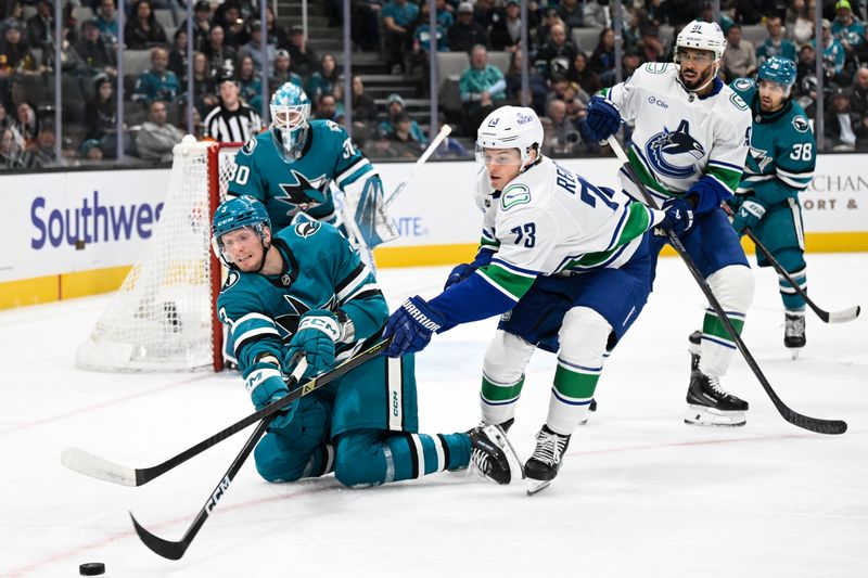 Nov 28, 2025; San Jose, California, USA; San Jose Sharks defenseman John Klingberg (3) clears the puck against Vancouver Canucks left winger Lukas Reichel (73) in the first period at SAP Center at San Jose. Mandatory Credit: Eakin Howard-Imagn Images