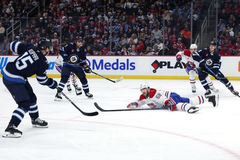 Dec 14, 2024; Winnipeg, Manitoba, CAN; Winnipeg Jets center Rasmus Kupari (15) passes the puck to Winnipeg Jets center Morgan Barron (36) over a fallen Montreal Canadiens defenseman David Savard (58) in the second period at Canada Life Centre. Mandatory Credit: James Carey Lauder-Imagn Images