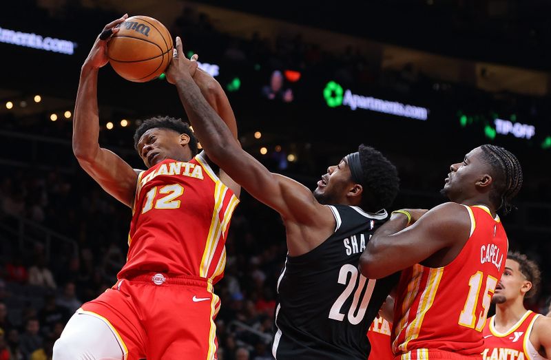 ATLANTA, GEORGIA - DECEMBER 06:  De'Andre Hunter #12 of the Atlanta Hawks battles for a rebound against Day'Ron Sharpe #20 of the Brooklyn Nets during the fourth quarter at State Farm Arena on December 06, 2023 in Atlanta, Georgia.  NOTE TO USER: User expressly acknowledges and agrees that, by downloading and/or using this photograph, user is consenting to the terms and conditions of the Getty Images License Agreement.  (Photo by Kevin C. Cox/Getty Images)