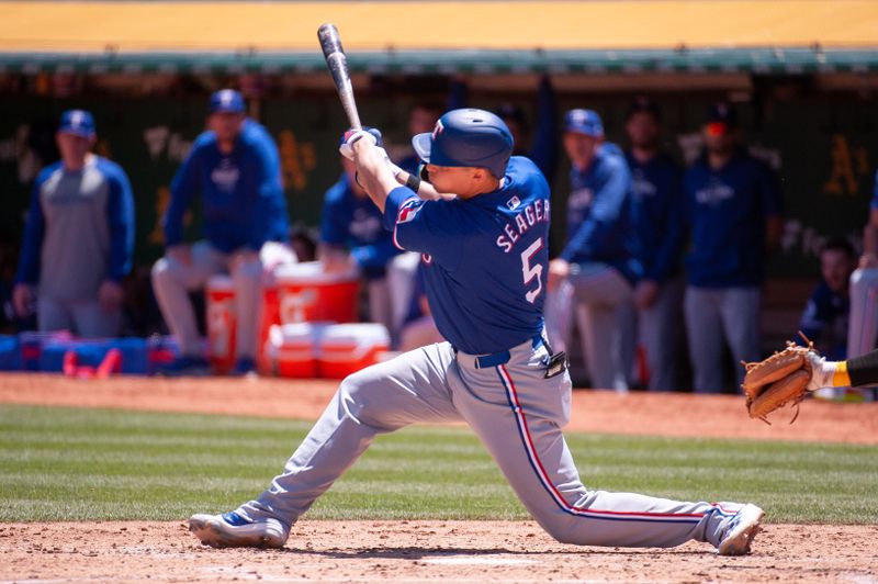 May 7, 2024; Oakland, California, USA; Texas Rangers shortstop Corey Seager (5) hits a single against the Oakland Athletics during the third inning at Oakland-Alameda County Coliseum. Mandatory Credit: Ed Szczepanski-USA TODAY Sports