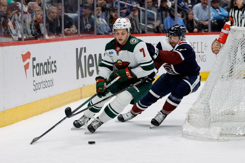 Apr 9, 2024; Denver, Colorado, USA; Minnesota Wild defenseman Brock Faber (7) controls the puck ahead of Colorado Avalanche right wing Brandon Duhaime (12) in the second period at Ball Arena. Mandatory Credit: Isaiah J. Downing-USA TODAY Sports