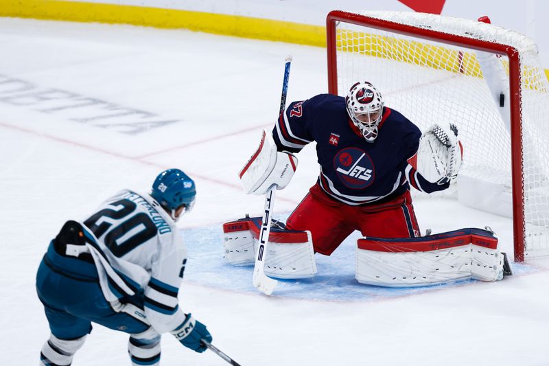 Oct 18, 2024; Winnipeg, Manitoba, CAN;  San Jose Sharks forward Fabian Zetterlund (20) scores on Winnipeg Jets goalie Connor Hellebuyck (37) during the third period at Canada Life Centre. Mandatory Credit: Terrence Lee-Imagn Images