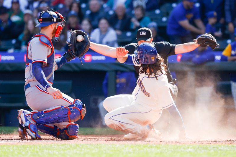 Oct 1, 2023; Seattle, Washington, USA; Seattle Mariners third baseman Eugenio Suarez (28, right) slides home to score a run against Texas Rangers catcher Jonah Heim (28) during the fourth inning at T-Mobile Park. Mandatory Credit: Joe Nicholson-USA TODAY Sports