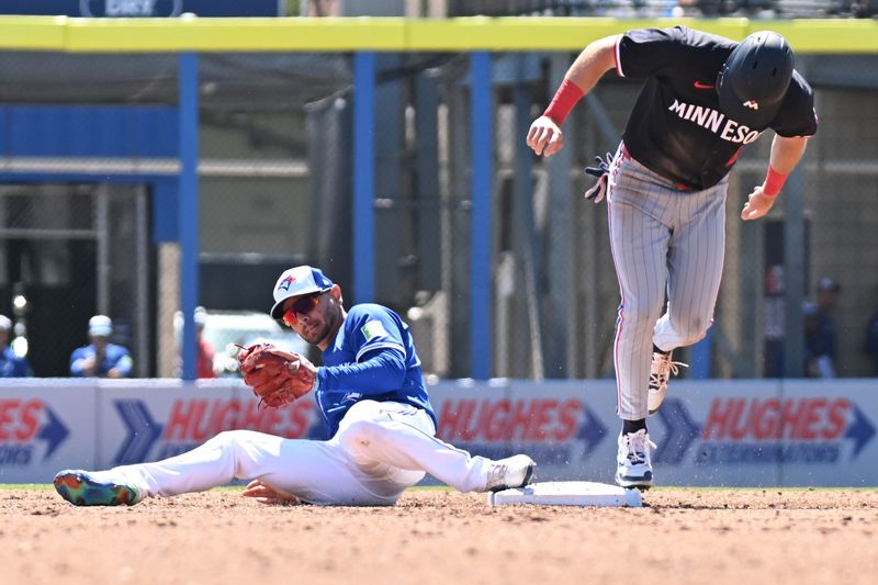 Mar 11, 2025; Dunedin, Florida, USA; Toronto Blue Jays second baseman Andres Gimenez (0) fields a throw as Minnesota Twins second baseman Edouard Julien (47) attempts to stay on the base in the third  inning   at TD Ballpark. Mandatory Credit: Jonathan Dyer-Imagn Images