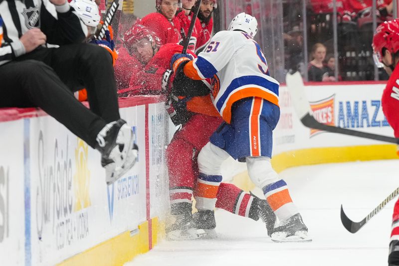 Oct 30, 2025; Raleigh, North Carolina, USA;  New York Islanders left wing Emil Heineman (51) checks Carolina Hurricanes defensemen Charles Alexis Legault (62) during the third period at Lenovo Center. Mandatory Credit: James Guillory-Imagn Images