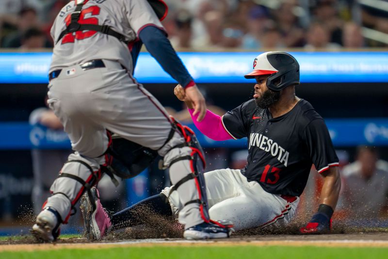 Aug 26, 2024; Minneapolis, Minnesota, USA; Minnesota Twins left fielder Manuel Margot (13) slides into home plate for a run before Atlanta Braves catcher Travis d'Arnaud (16) can make a tag in the first inning at Target Field. Mandatory Credit: Jesse Johnson-USA TODAY Sports