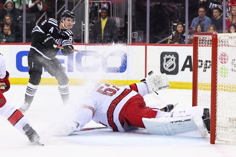 Mar 9, 2024; Newark, New Jersey, USA; Carolina Hurricanes goaltender Pyotr Kochetkov (52) makes a save on New Jersey Devils center Jack Hughes (86) during the second period at Prudential Center. Mandatory Credit: Ed Mulholland-USA TODAY Sports