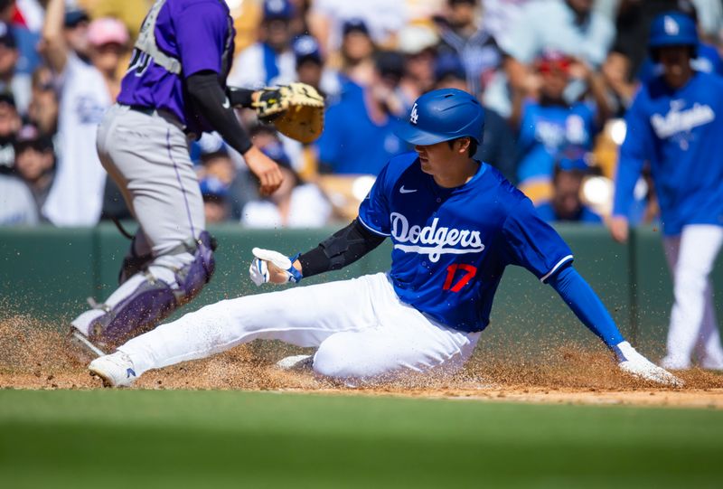 Mar 3, 2024; Phoenix, Arizona, USA; Los Angeles Dodgers designated hitter Shohei Ohtani slides into home plate to score a run against the Colorado Rockies during a spring training game at Camelback Ranch-Glendale. Mandatory Credit: Mark J. Rebilas-USA TODAY Sports