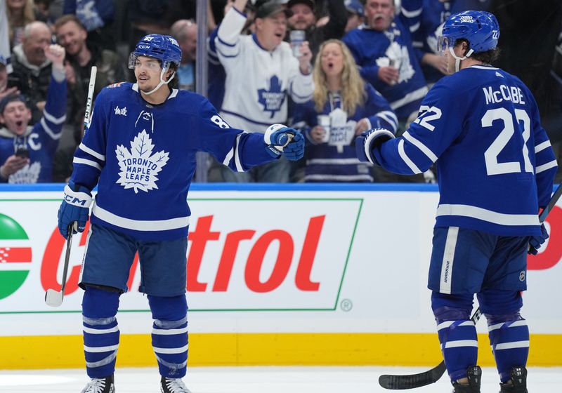 Jan 9, 2024; Toronto, Ontario, CAN; Toronto Maple Leafs left wing Nicholas Robertson (89) scores a goal and celebrates with defenseman Jake McCabe (22) against the San Jose Sharks during the third period at Scotiabank Arena. Mandatory Credit: Nick Turchiaro-USA TODAY Sports