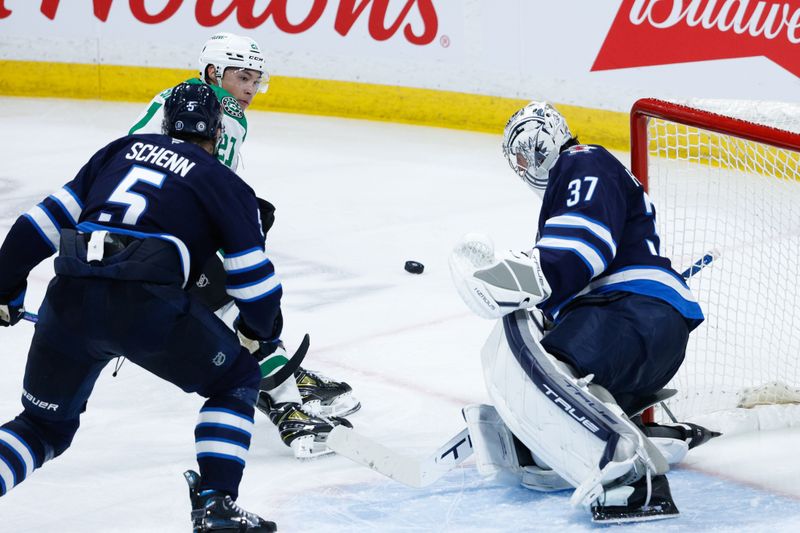 Mar 14, 2025; Winnipeg, Manitoba, CAN;  Winnipeg Jets goalie Connor Hellebuyck (37) makes a save on a shot by Dallas Stars forward Jason Robertson (21) during the third period at Canada Life Centre. Mandatory Credit: Terrence Lee-Imagn Images