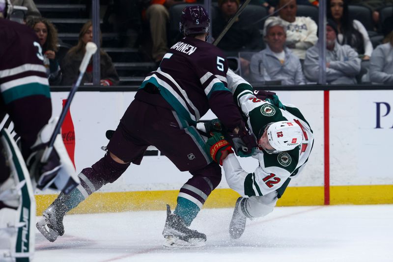 Mar 19, 2024; Anaheim, California, USA; Anaheim Ducks defenseman Urho Vaakanainen (5) checks Minnesota Wild left wing Matt Boldy (12) during the third period of a game at Honda Center. Mandatory Credit: Jessica Alcheh-USA TODAY Sports