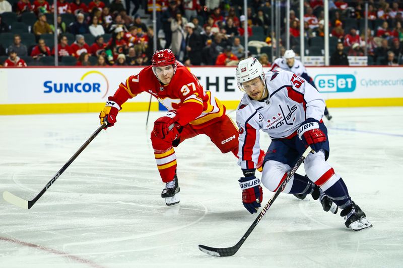Jan 23, 2026; Calgary, Alberta, CAN; Washington Capitals center Ethen Frank (53) controls the puck against Calgary Flames defenseman Yan Kuznetsov (37) during the third period at Scotiabank Saddledome. Mandatory Credit: Sergei Belski-Imagn Images