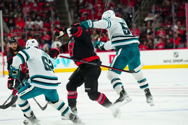 Oct 27, 2023; Raleigh, North Carolina, USA; Carolina Hurricanes defenseman Dmitry Orlov (7) checks San Jose Sharks right wing Givani Smith (54) during the third period at PNC Arena. Mandatory Credit: James Guillory-USA TODAY Sports