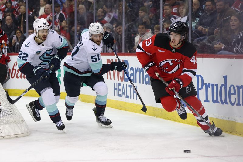 Dec 6, 2024; Newark, New Jersey, USA; New Jersey Devils defenseman Luke Hughes (43) skates with the puck while being pursued by Seattle Kraken right wing Oliver Bjorkstrand (22) and center Shane Wright (51) during the first period at Prudential Center. Mandatory Credit: Ed Mulholland-Imagn Images