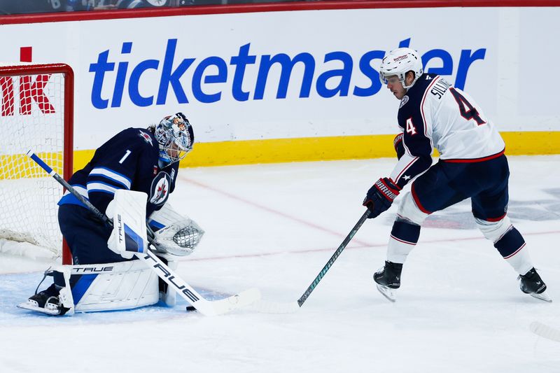 Nov 18, 2025; Winnipeg, Manitoba, CAN;  Winnipeg Jets goalie Eric Comrie (1) makes a save on a shot by Columbus Blue Jackets forward Cole Sillinger(4) during the second period at Canada Life Centre. Mandatory Credit: Terrence Lee-Imagn Images