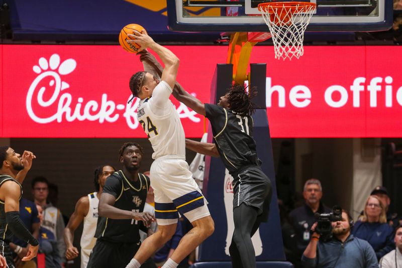 Feb 20, 2024; Morgantown, West Virginia, USA; West Virginia Mountaineers forward Patrick Suemnick (24) grabs a rebound over UCF Knights forward Thierno Sylla (31) during the first half at WVU Coliseum. Mandatory Credit: Ben Queen-USA TODAY Sports