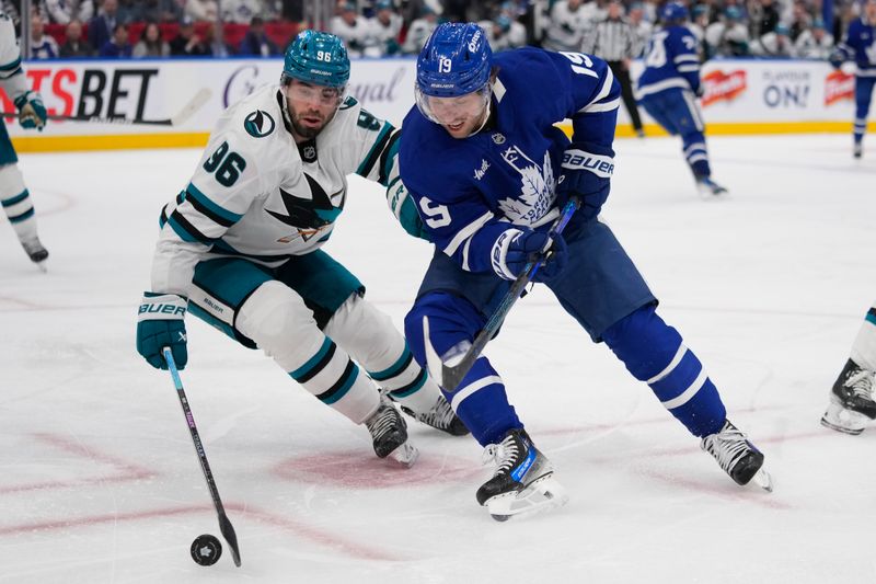 Mar 3, 2025; Toronto, Ontario, CAN; Toronto Maple Leafs forward Calle Jarnkrok (19) and San Jose Sharks defenseman Jake Walman (96) battle for a puck during the period at Scotiabank Arena. Mandatory Credit: John E. Sokolowski-Imagn Images