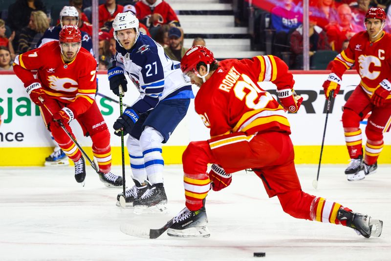 Oct 4, 2024; Calgary, Alberta, CAN; Winnipeg Jets left wing Nikolaj Ehlers (27) passes the puck against the Calgary Flames during the first period at Scotiabank Saddledome. Mandatory Credit: Sergei Belski-Imagn Images