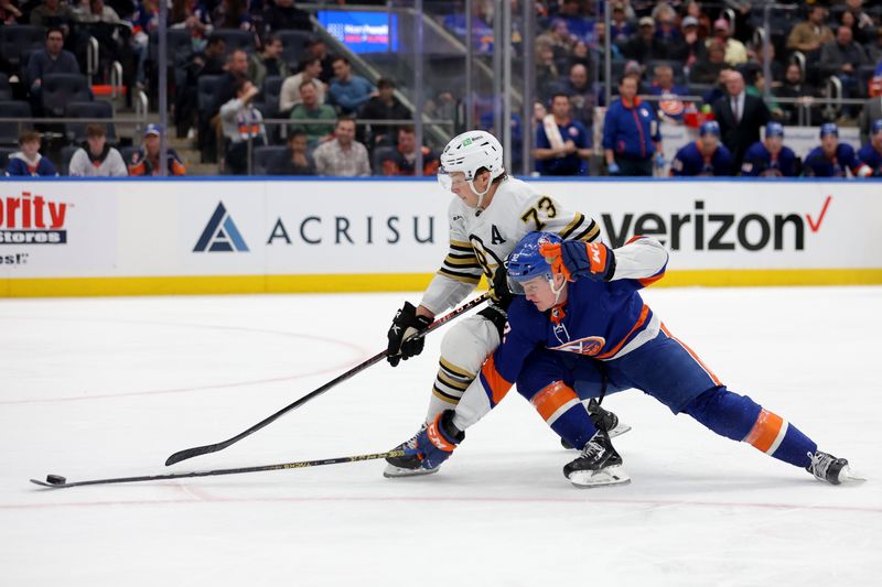 Mar 2, 2024; Elmont, New York, USA; Boston Bruins defenseman Charlie McAvoy (73) and New York Islanders center Kyle MacLean (32) fight for the puck during the second period at UBS Arena. Mandatory Credit: Brad Penner-USA TODAY Sports