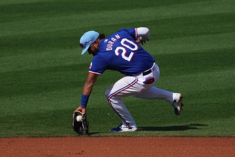 Feb 28, 2024; Surprise, Arizona, USA; Texas Rangers shortstop Ezequiel Duran (20) fields a ground ball against the Los Angeles Dodgers during the third inning at Surprise Stadium. Mandatory Credit: Joe Camporeale-USA TODAY Sports